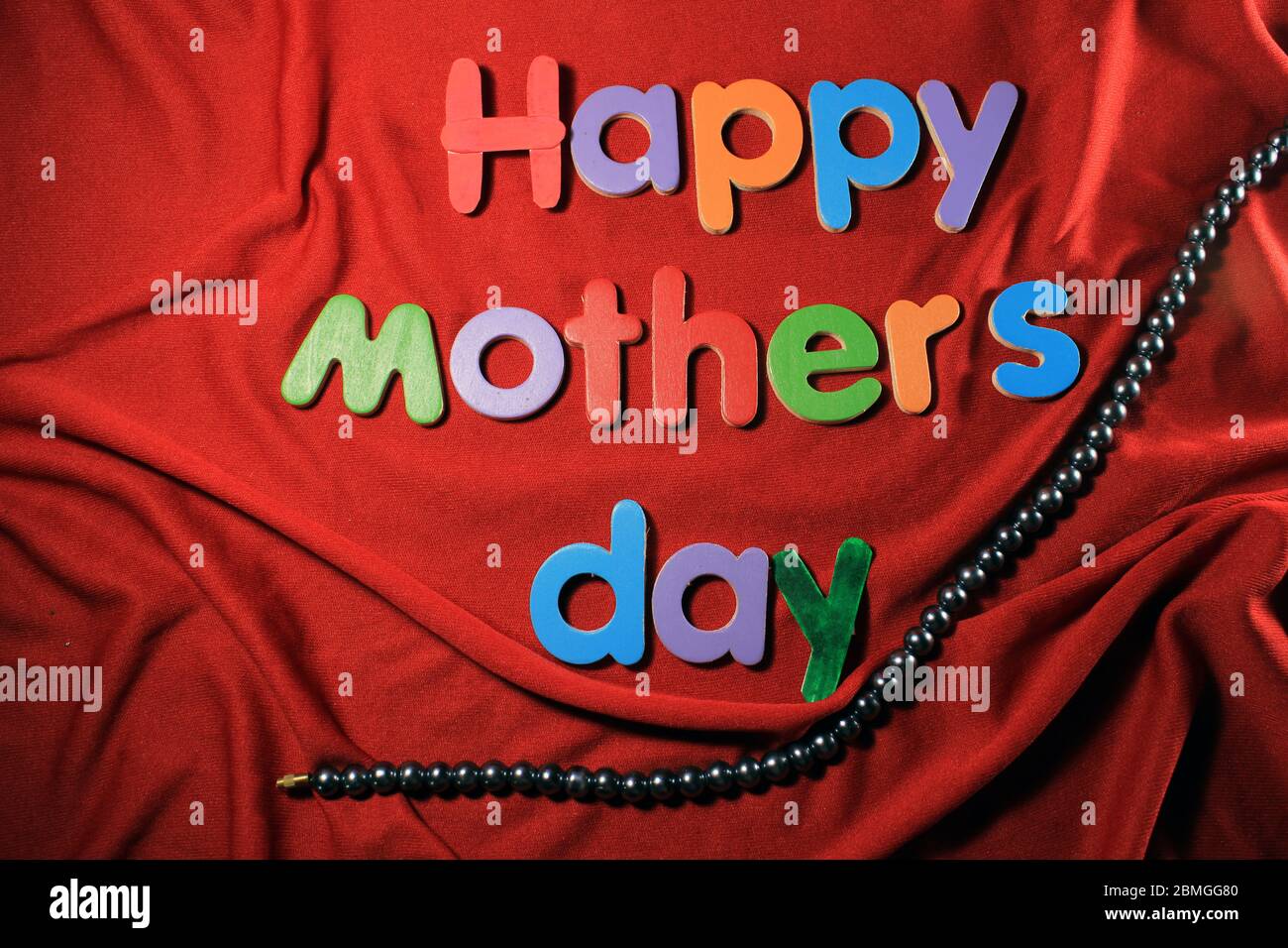 Happy Mother's Day written on red cloth texture background. Happy Mother's day written by colorful alphabet blocks. Stock Photo