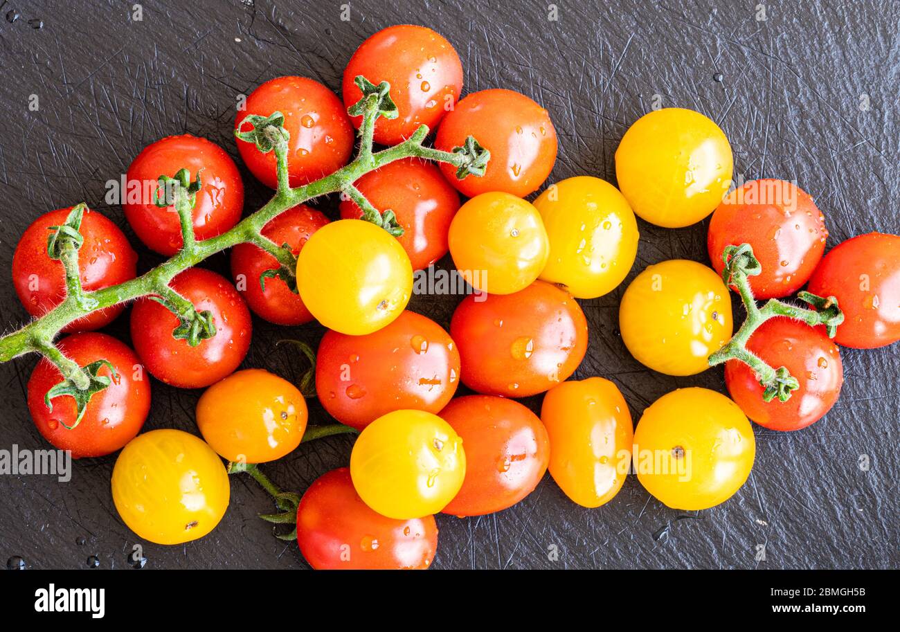 Fresh red and yellow cherry tomatoes over a black slate board Stock ...