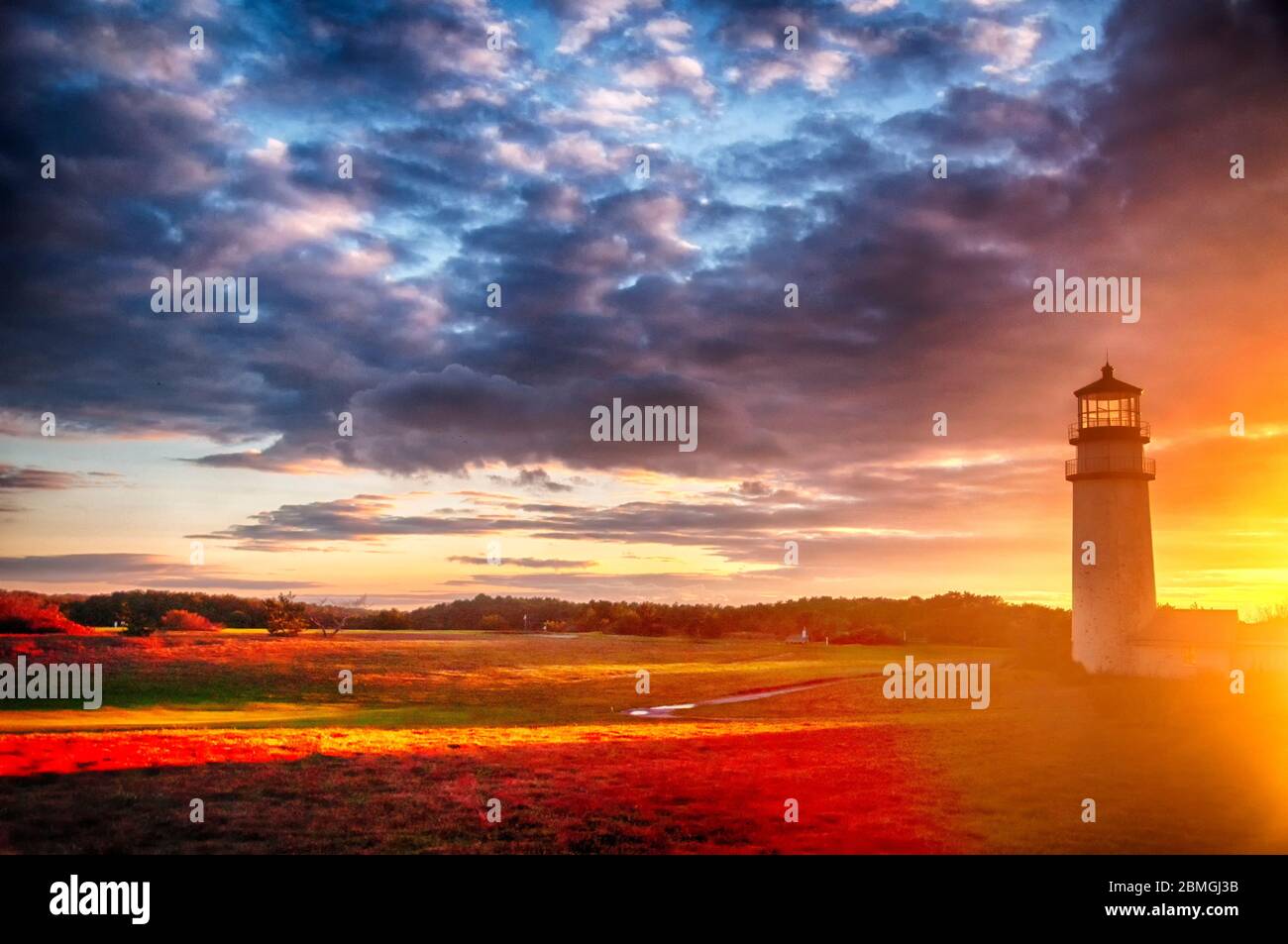 The highland lighthouse in north truro massachusetts on cape cod against a dramatic orange sunset sky. Stock Photo