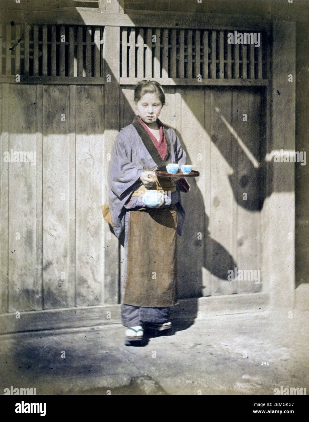 [ 1860s Japan - Japanese Woman Serving Tea ] —   A waitress or servant with a teapot and cups.  19th century vintage albumen photograph. Stock Photo