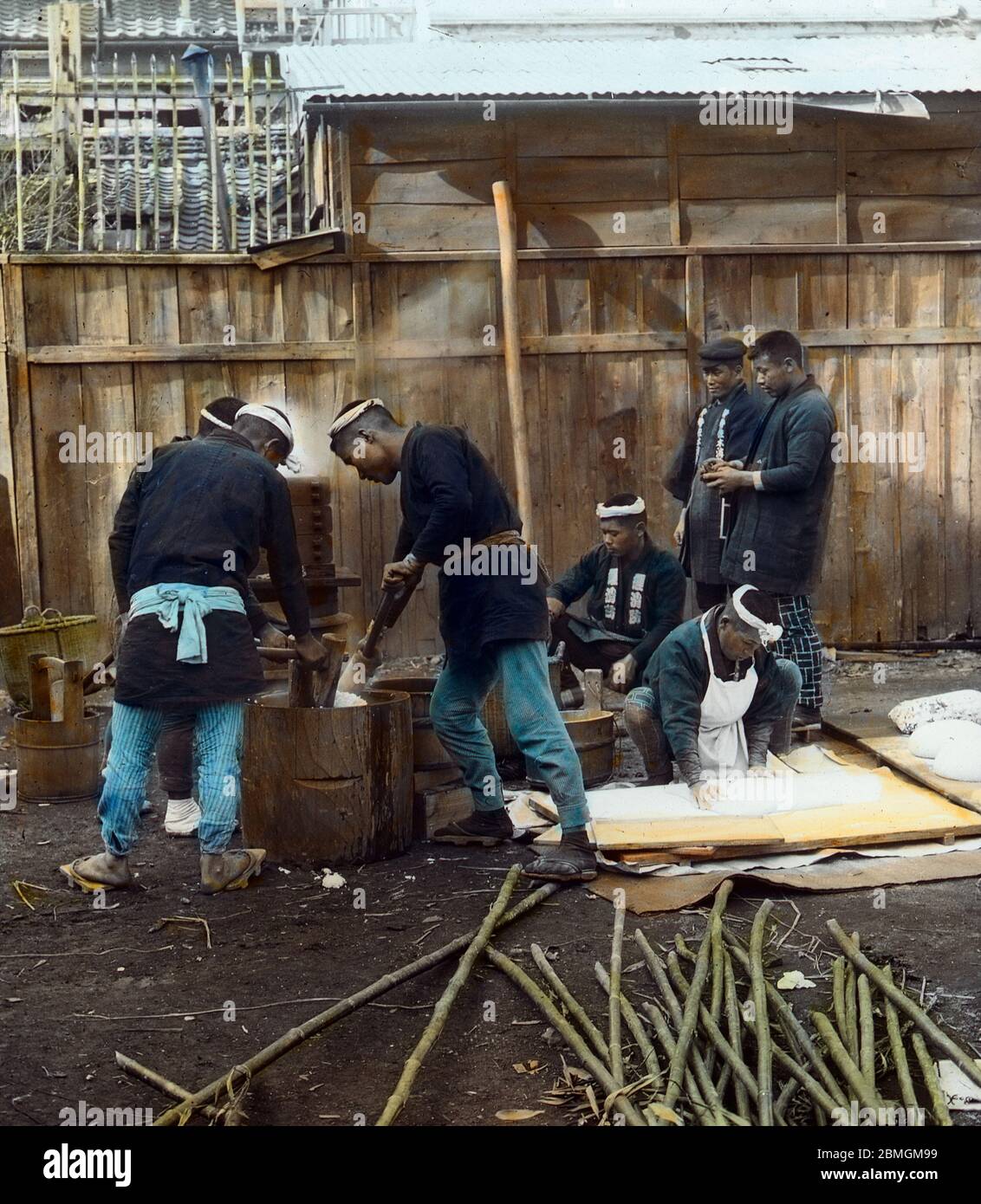 [ 1900s Japan - Japanese Pounding Rice ] —   Pounding glutinous rice to make mochi rice cakes.  Original text: 'Making rice cake by beating in a wooden mortar.'  20th century vintage glass slide. Stock Photo
