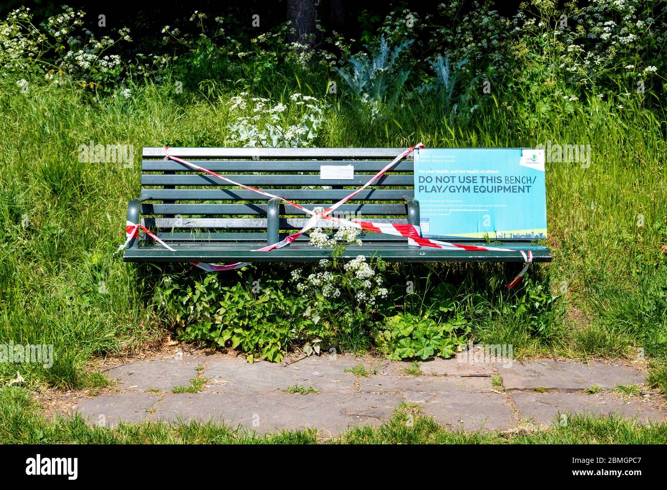 9th May 2020, London, UK - Bench taped over due to government restrictions to prevent people from using it during the Coronavirus outbreak lockdown at Tower Hamlets Cemetery Park, sign saying 'Do Not Use this Bench / Play / Gym Equipment' Stock Photo