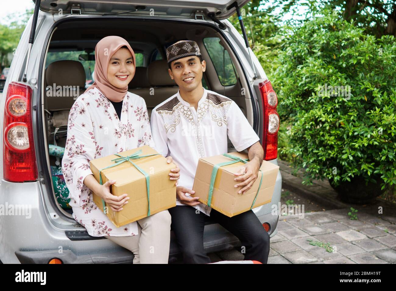 muslim couple travelling by car. man and woman sitting in the car trunk ...