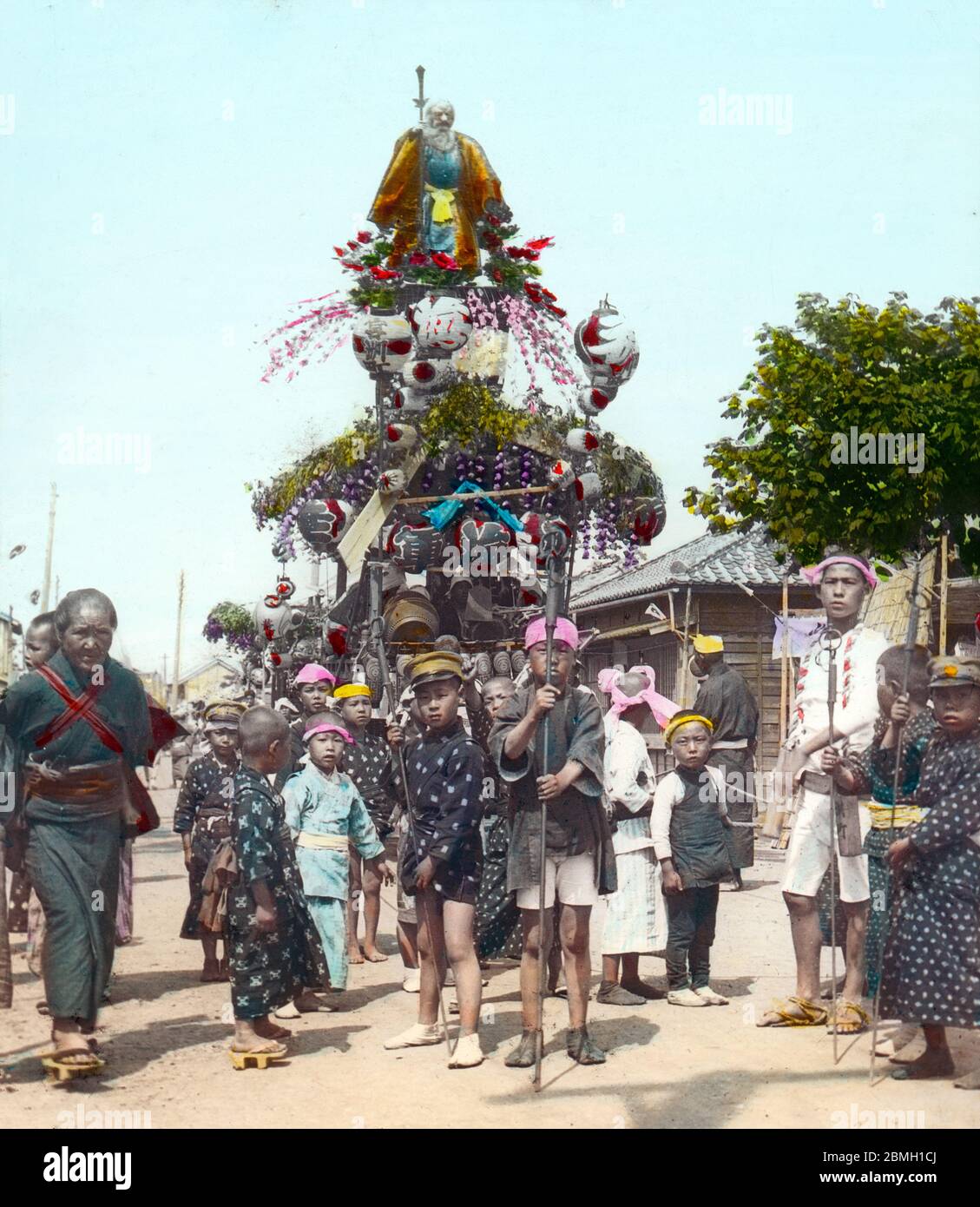 [ 1900s Japan - Japanese Festival Float ] —   A danjiri festival float pulled by children at a matsuri (religious festival).  Original text: 'A decorated car with a musical band on it draw by an ox on the festival day.'  20th century vintage glass slide. Stock Photo