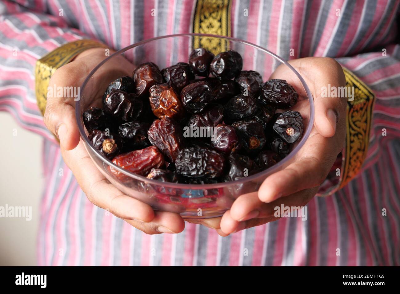 the concept of ramadan, hand holding a bowl of date fruits  Stock Photo
