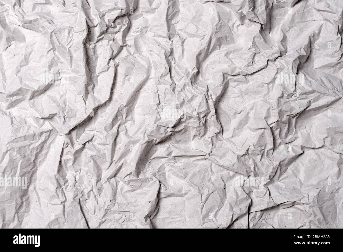 Crumpled gray paper texture. Wrinkled paper background with cracks and kinks. Stock Photo