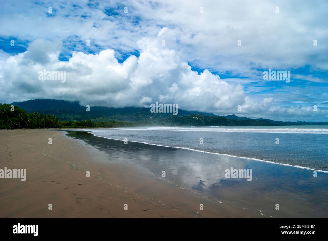 Curved Beach Below the Mountains Stock Photo