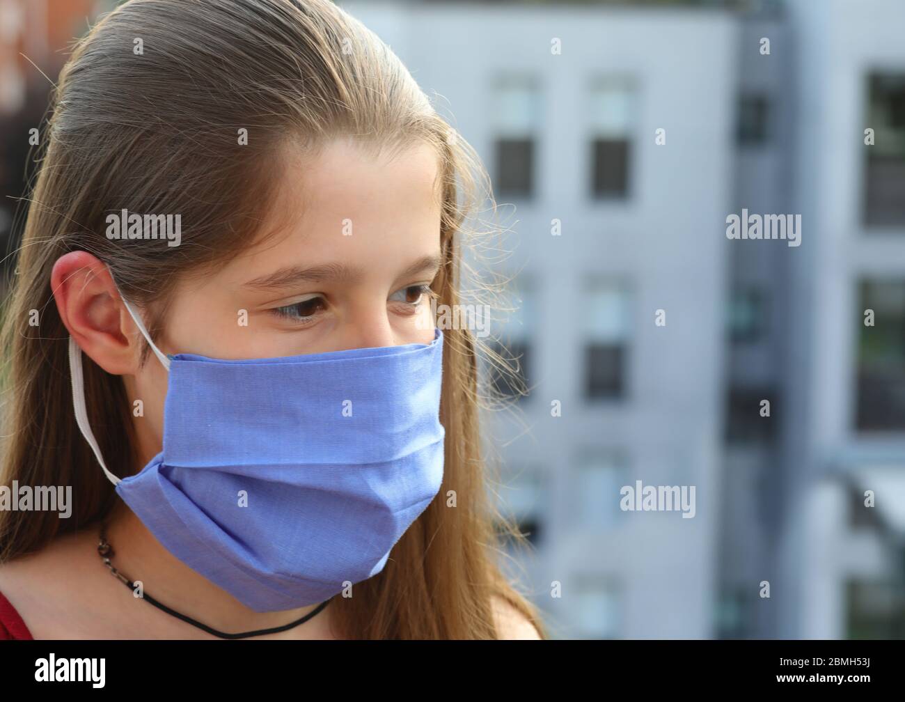 thoughtful young Caucasian nurse with long brown hair and blue surgical mask in hospital Stock Photo