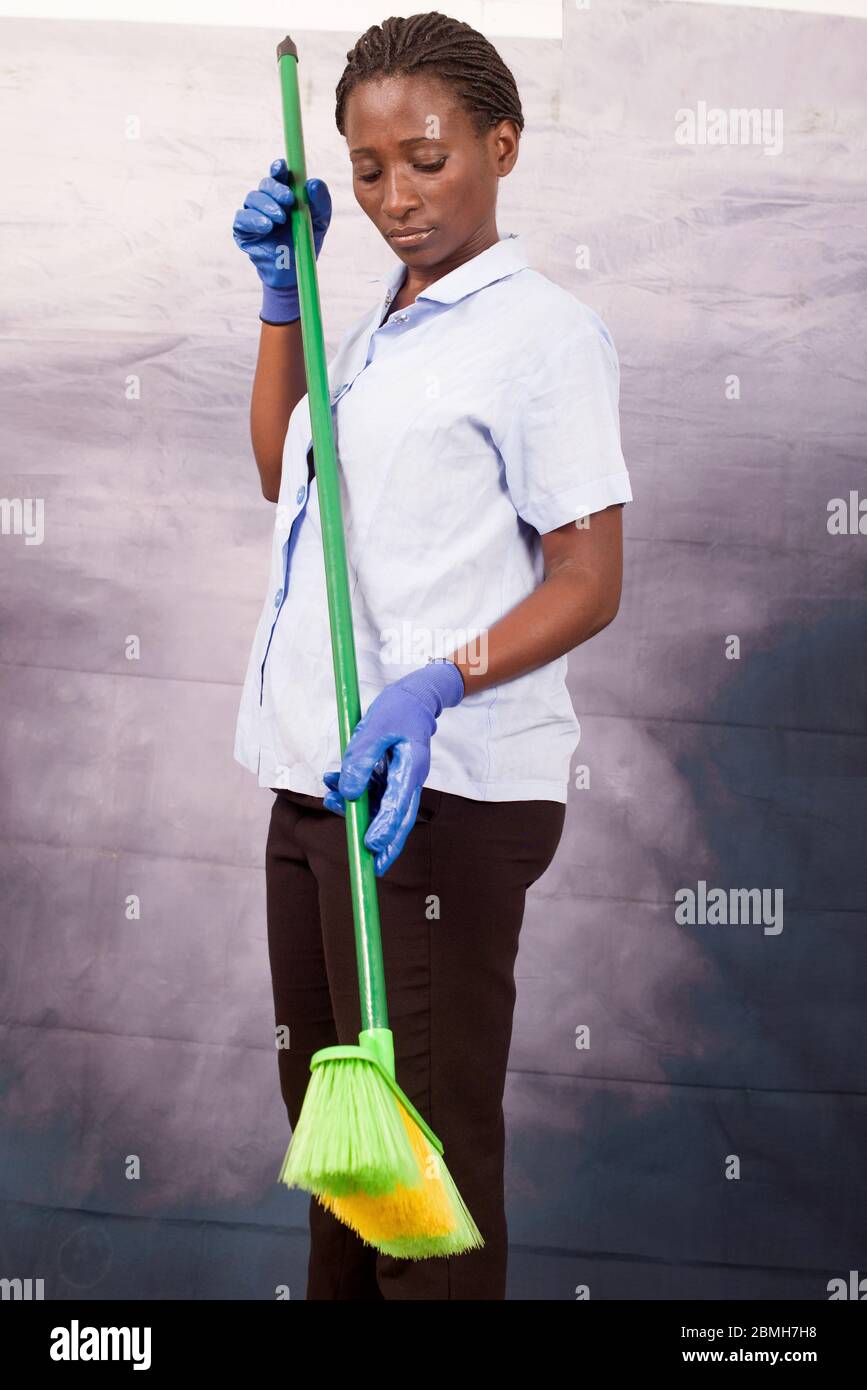 fun housekeeper doing an indoor cleaning with a sweeping Stock Photo