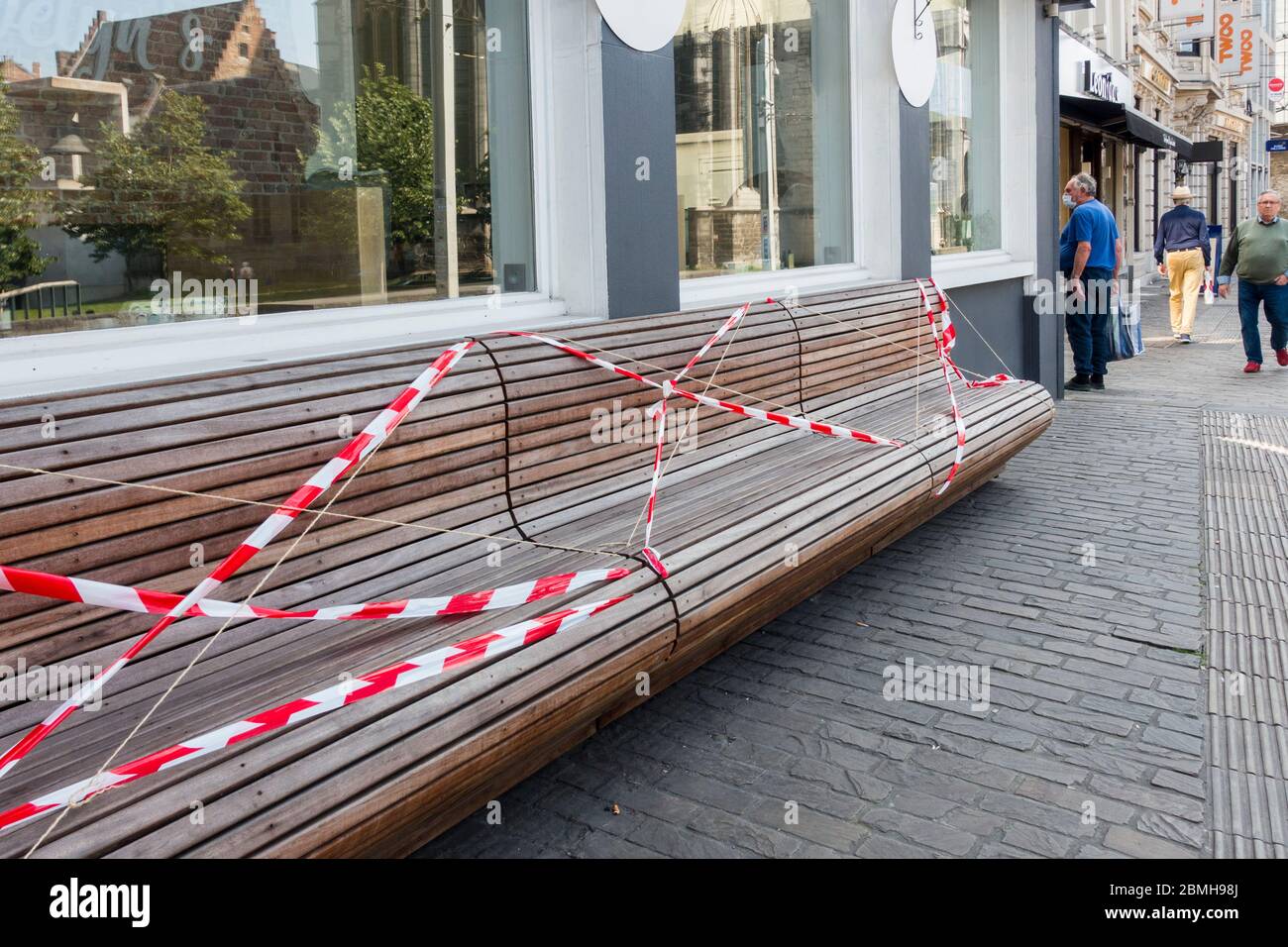 Public bench closed and sealed off with tape to prevent sitting due to 2020 COVID-19 / coronavirus / corona virus pandemic in the city Ghent, Belgium Stock Photo