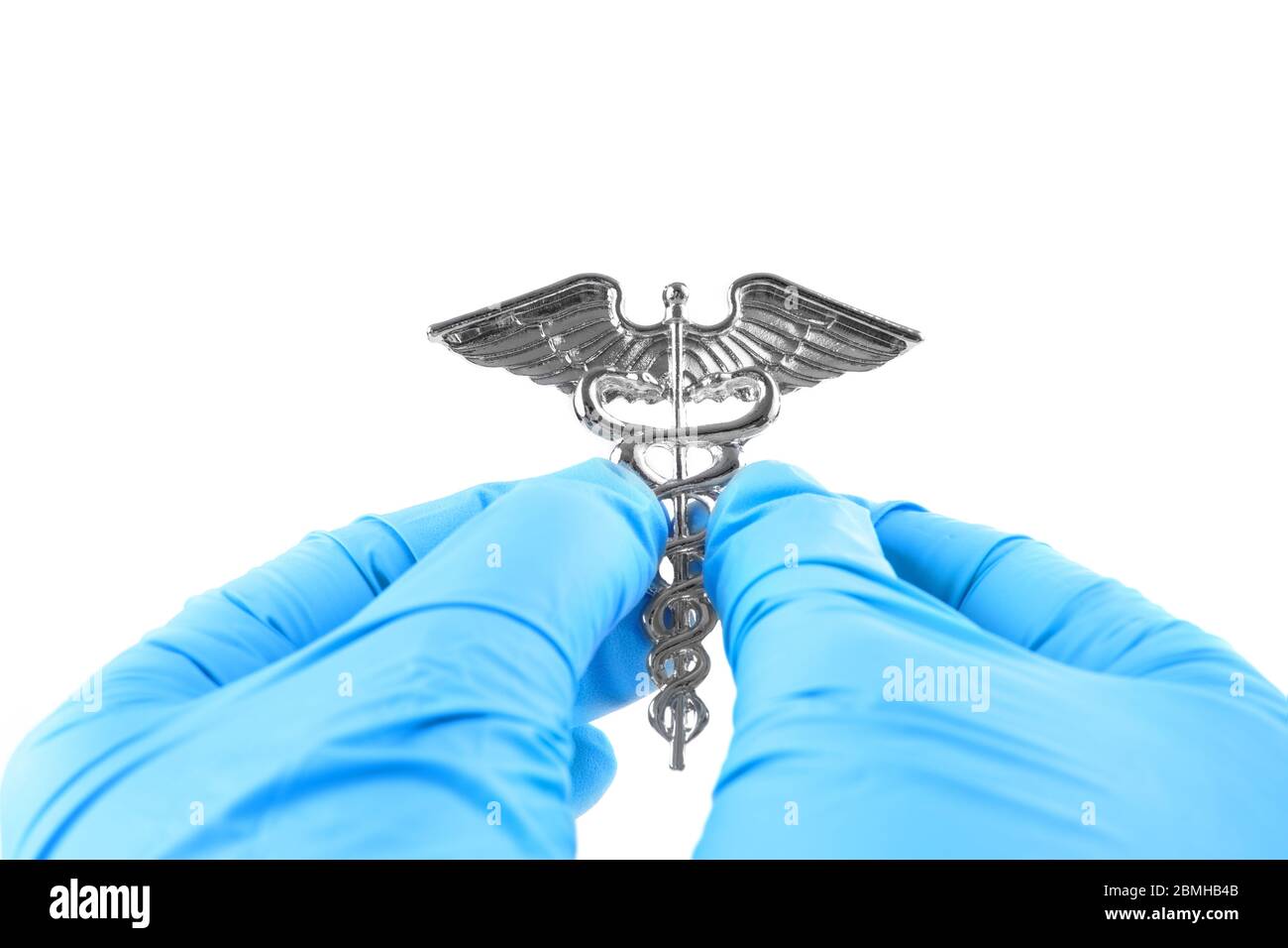Female hands in blue disposable gloves hold a medical insignia of Caduceus isolated on white. Stock Photo