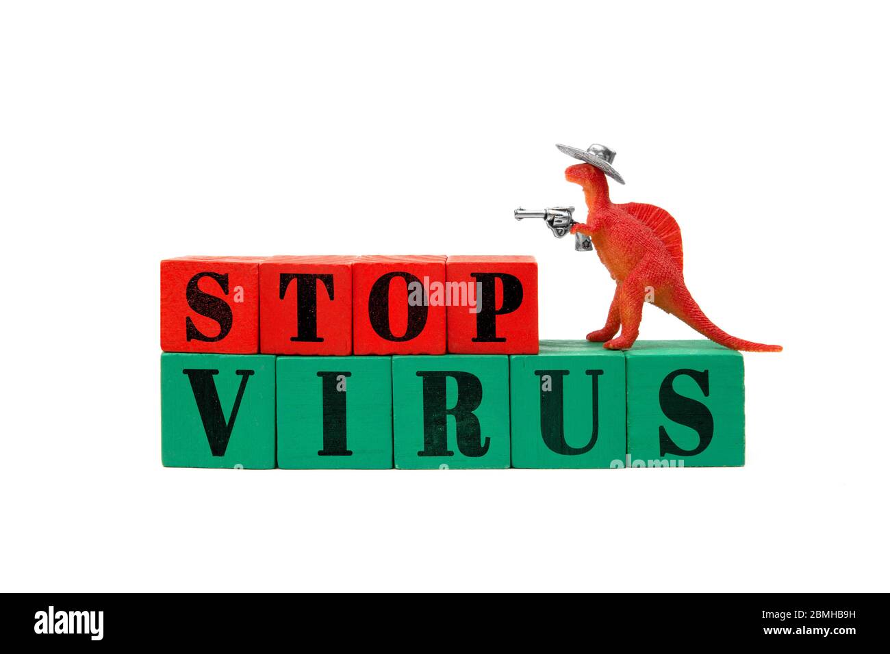 A small toy dinosaur wearing a cowboy hat and holding a revolver in his arm stands on a line of colored wooden blocks reading Stop Virus lettering. Stock Photo