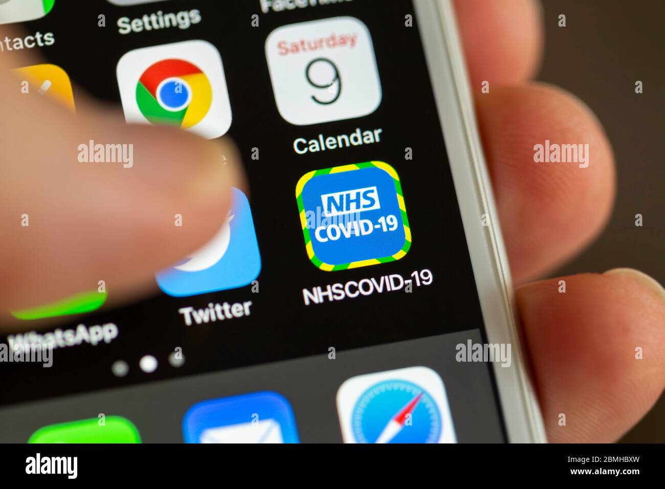 BATH, UK - MAY 9, 2020 : Close-up of the NHS COVID-19 contact tracing app on an iPhone screen with a thumb hovering above it. Stock Photo