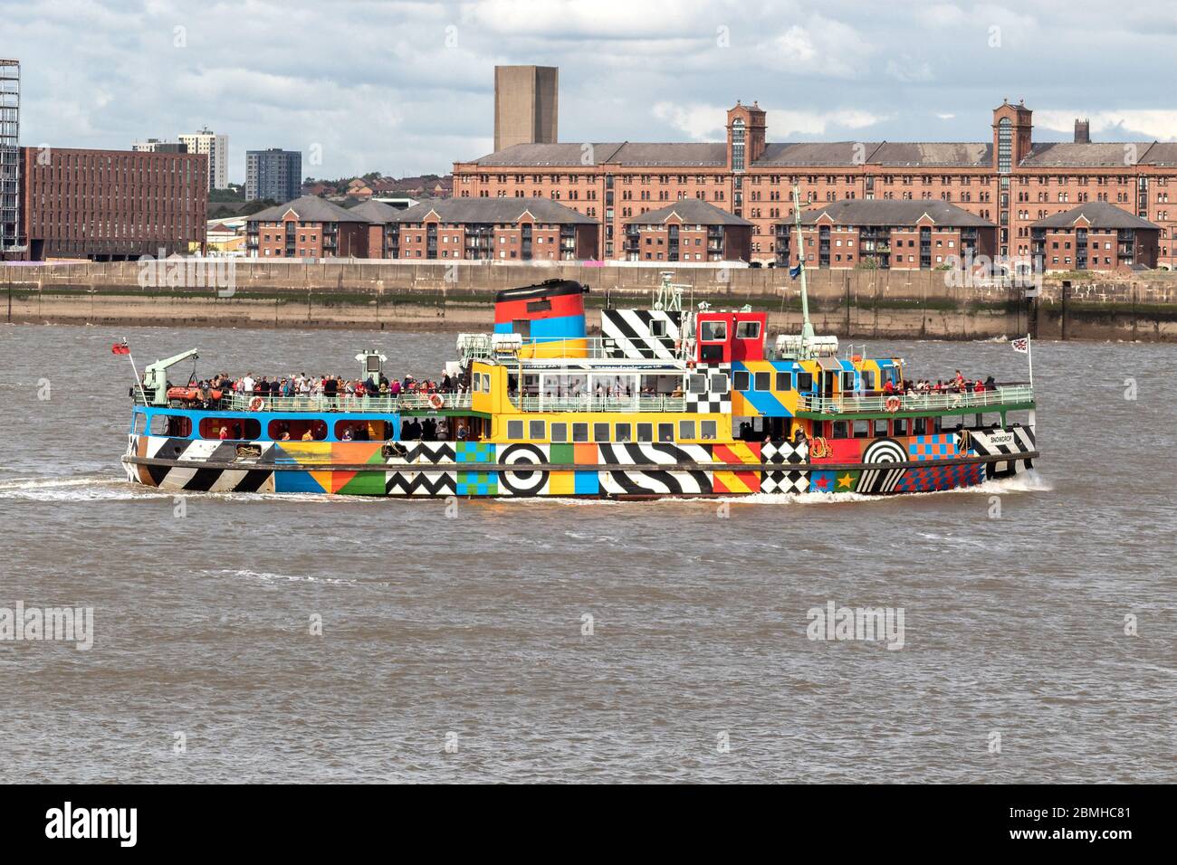 Mersey river ferry 'Snowdrop' in dazzle livery designed by Sir Peter Blake against Liverpool city skyline. Stock Photo