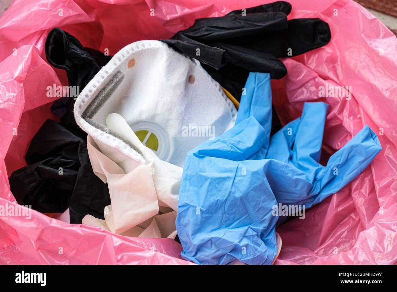 Medical used protective mask and gloves in garbage bin,coronavirus disease equipment items Stock Photo