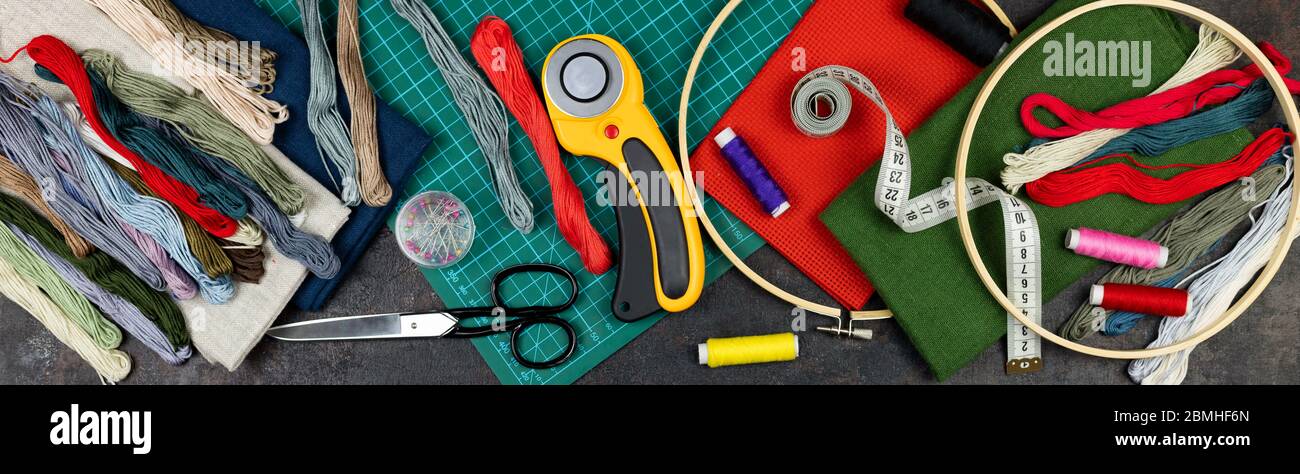 there are quilting, embroidery and sewing tools on the table. patchwork knife, scissors, lined cutting mat, self-locking, threads, measuring tape, sew Stock Photo