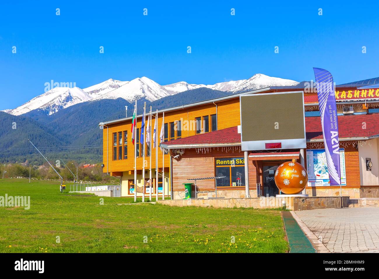 Bulgaria, Bansko - May 5, 2020: Big yellow New Year ball, Bansko loves you near gondola ski lift station and snow mountains spring panorama Stock Photo