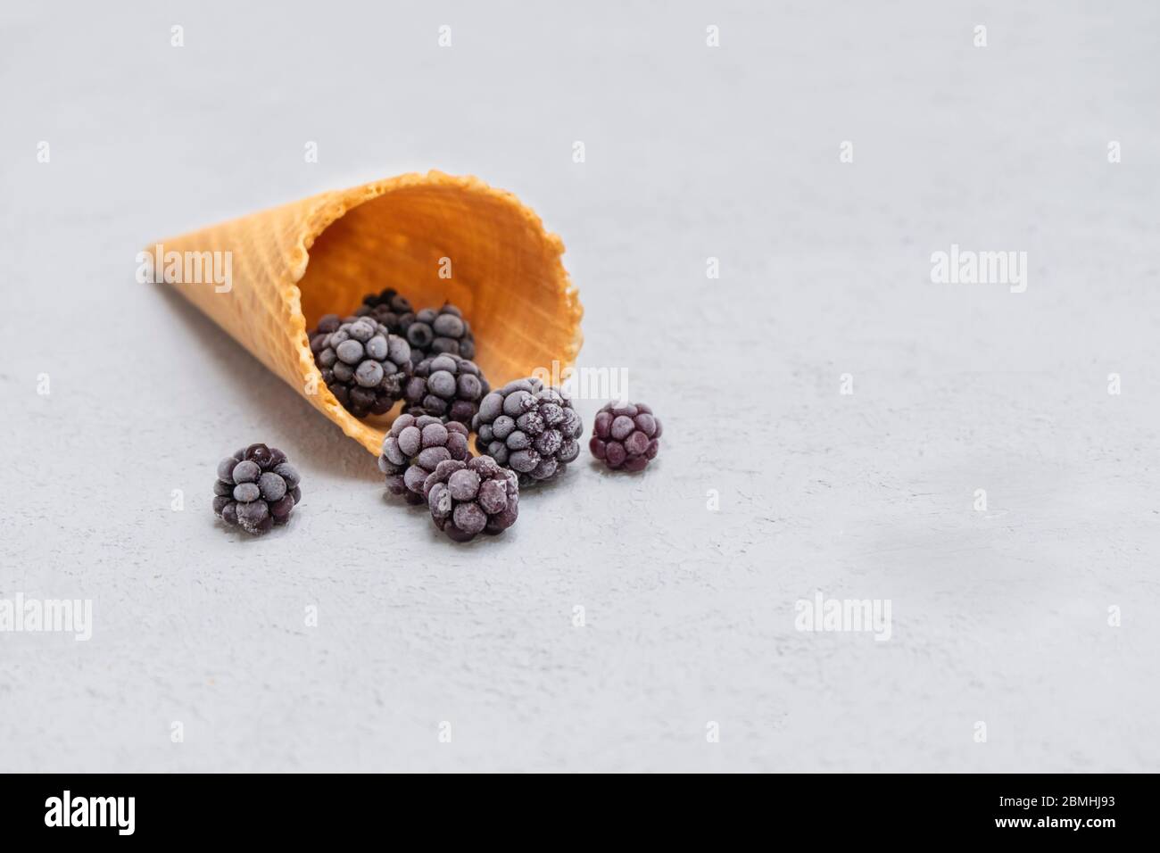 Frozen blackberries in a waffle cone on neutral background with space for text Stock Photo
