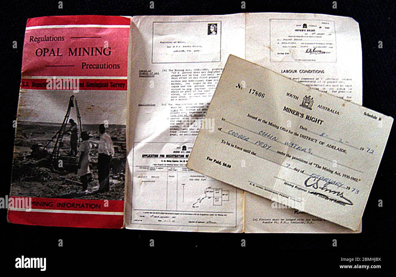 Opal mining in Coober Pedy, central Australia (geographically South Australia). The town is known as the 'Opal capital of the world'.  The picture shows a 1972 Miner's Right, a document to allow an individual to mine for the precious gemstone for one year. Also in the picture is an accompanying leaflet containing regulations, conditions, precautions  and how to stake a claim. The first opal was found in Coober Pedy on 1 February 1915  by Wille Hutchison and the town now supplies most of the world's opal. Most of the population and many of the businesses are  built in underground   dugouts. Stock Photo