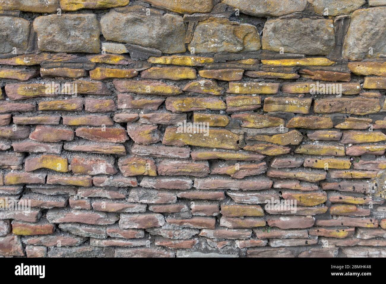 a close up view of a stone wall with moss and grouting around it Stock