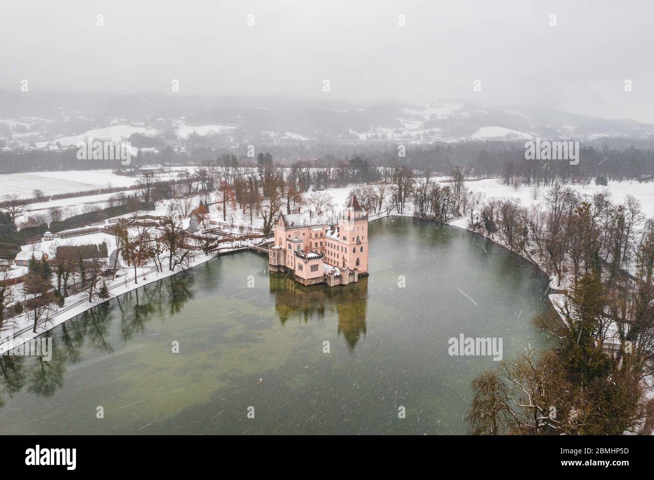 Aerial drone shot of Anif Schloss moated castle in artificial pond at Salzburg outskirts in heavy snow during winter time Stock Photo