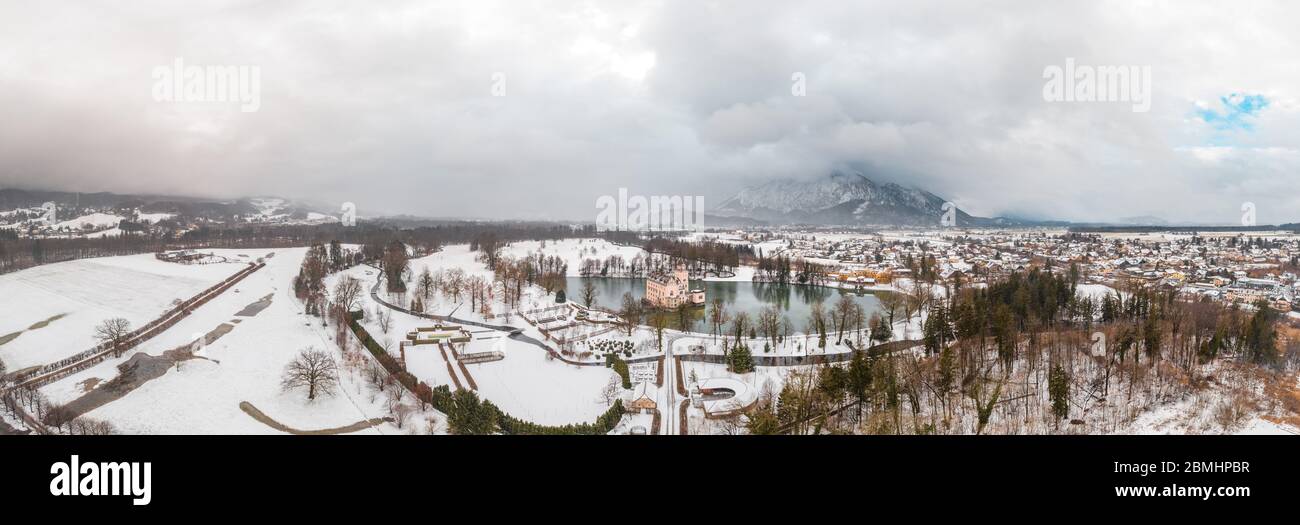 Panoramic aerial drone shot of Anif Schloss moated castle in artificial pond at Salzburg outskirts in heavy snow during winter time Stock Photo