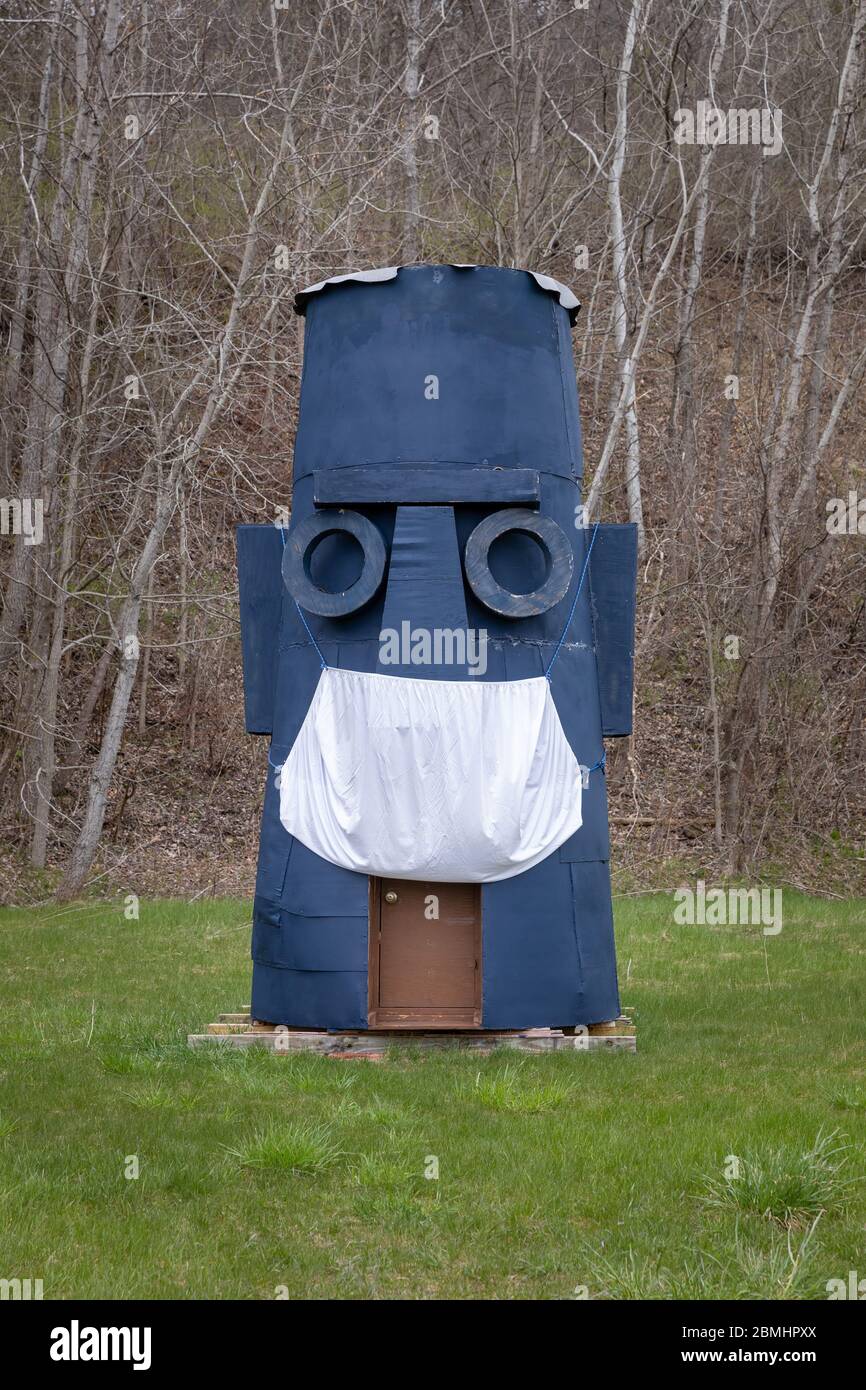 Palatine Bridge, NY: Plywood Tiki totem has donned a bed sheet face mask in the time of COVID. Stock Photo
