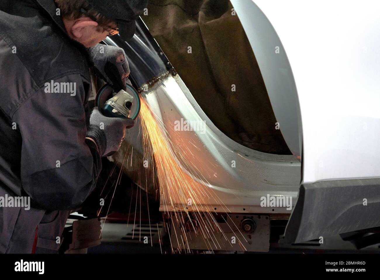 Repair service worker fix damaged car. Working with angle grinder to fix metal body. Stock Photo