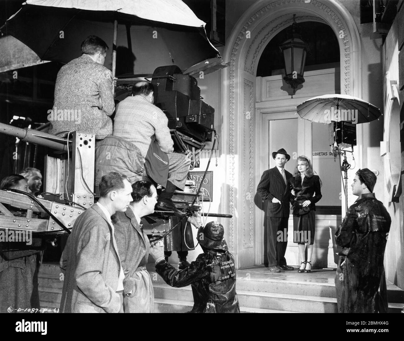 Director CHARLES VIDOR (on camera crane at left) Cinematographer RUDOLPH MATE (second left standing) GLENN FORD and RITA HAYWORTH with Film Crew on set candid filming GILDA 1946 director CHARLES VIDOR gowns JEAN LOUIS producer VIRGINIA VAN UPP Columbia Pictures Corporation Stock Photo