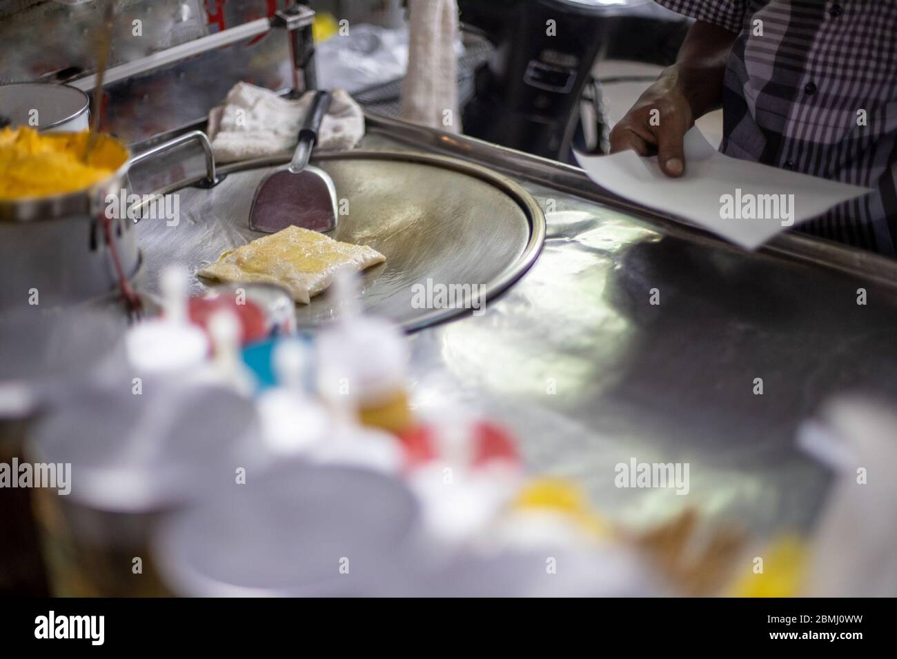 process for the preparation of tasty traditional Thai pancakes on a street counter. male hands fry a pancake in oil. local specialty. Stock Photo
