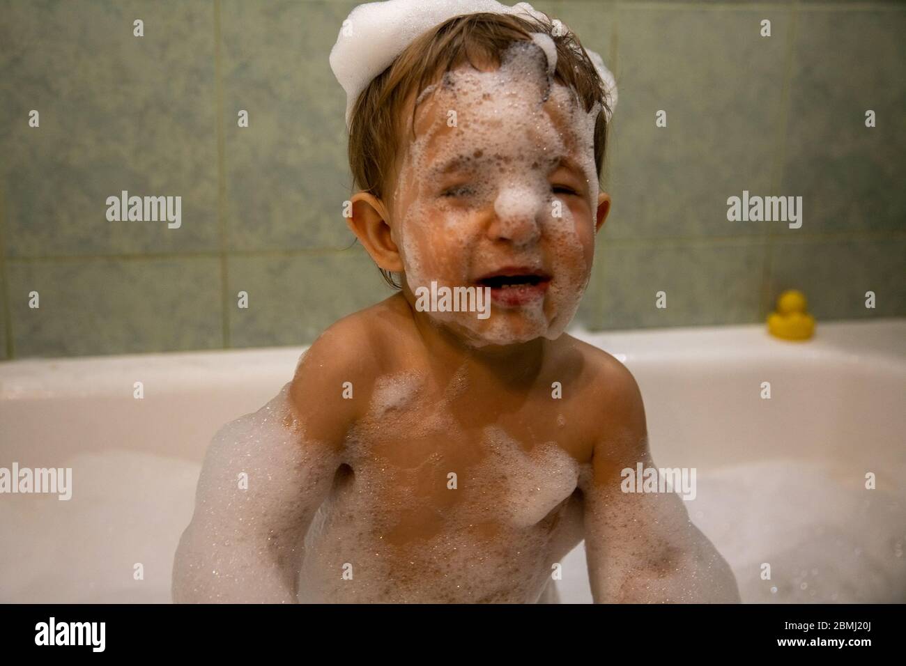 Cute baby boy taking a bath. Funny toddler in a bathtub in a soap foam