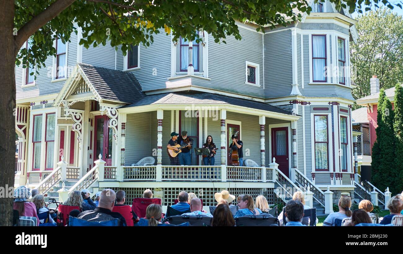 Crowd watched musicians perform from a porch in a neighborhood residential historic district on a sunny day. Stock Photo