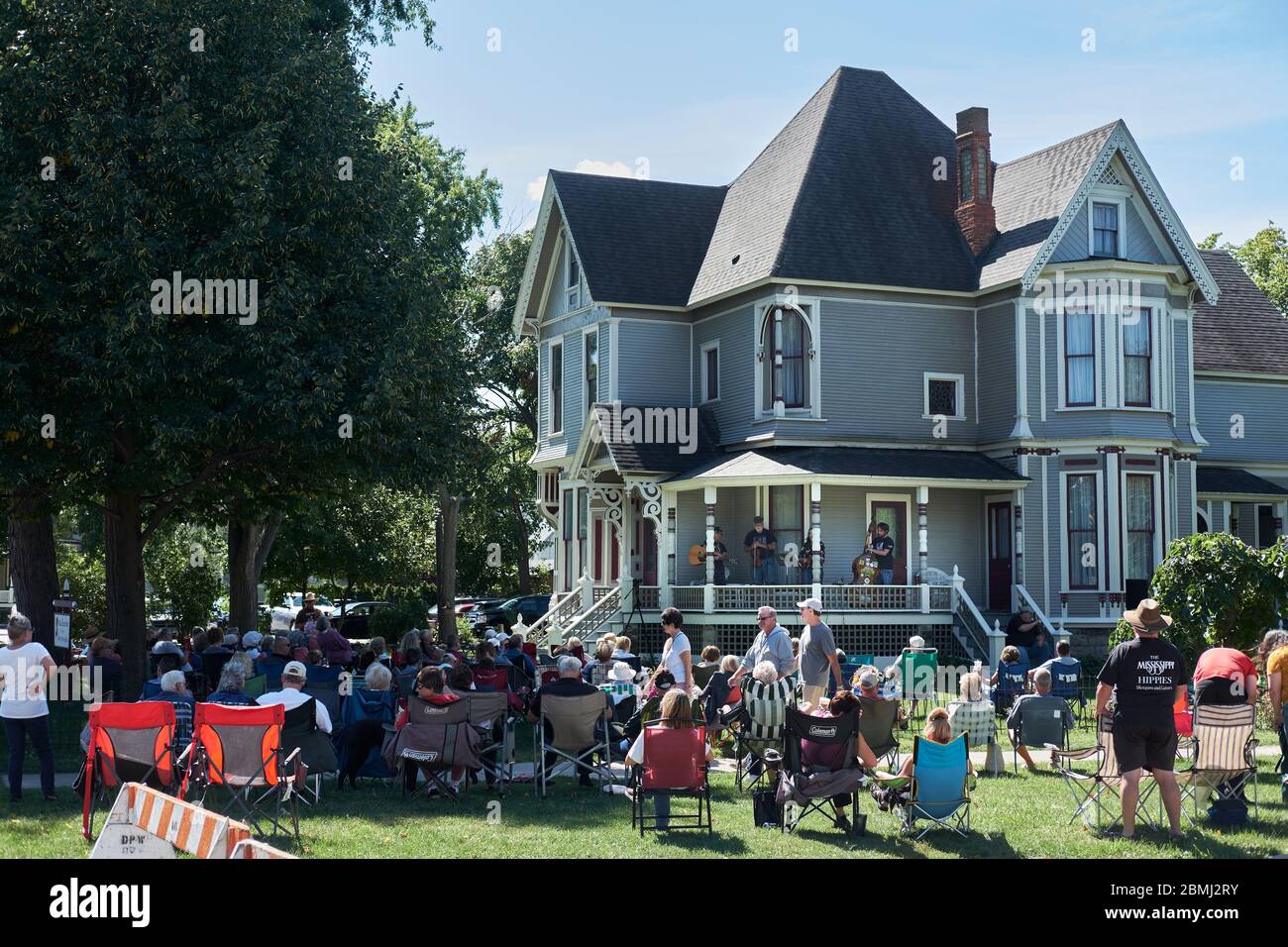Crowd watched musicians perform from a porch in a neighborhood residential historic district on a sunny day. Stock Photo