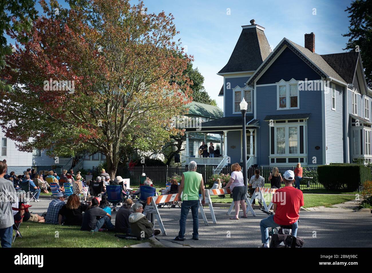 Crowd outside older house in historic district gathers to watch musicians perform at a free porch concert in small town Port Huron, MI USA. Stock Photo