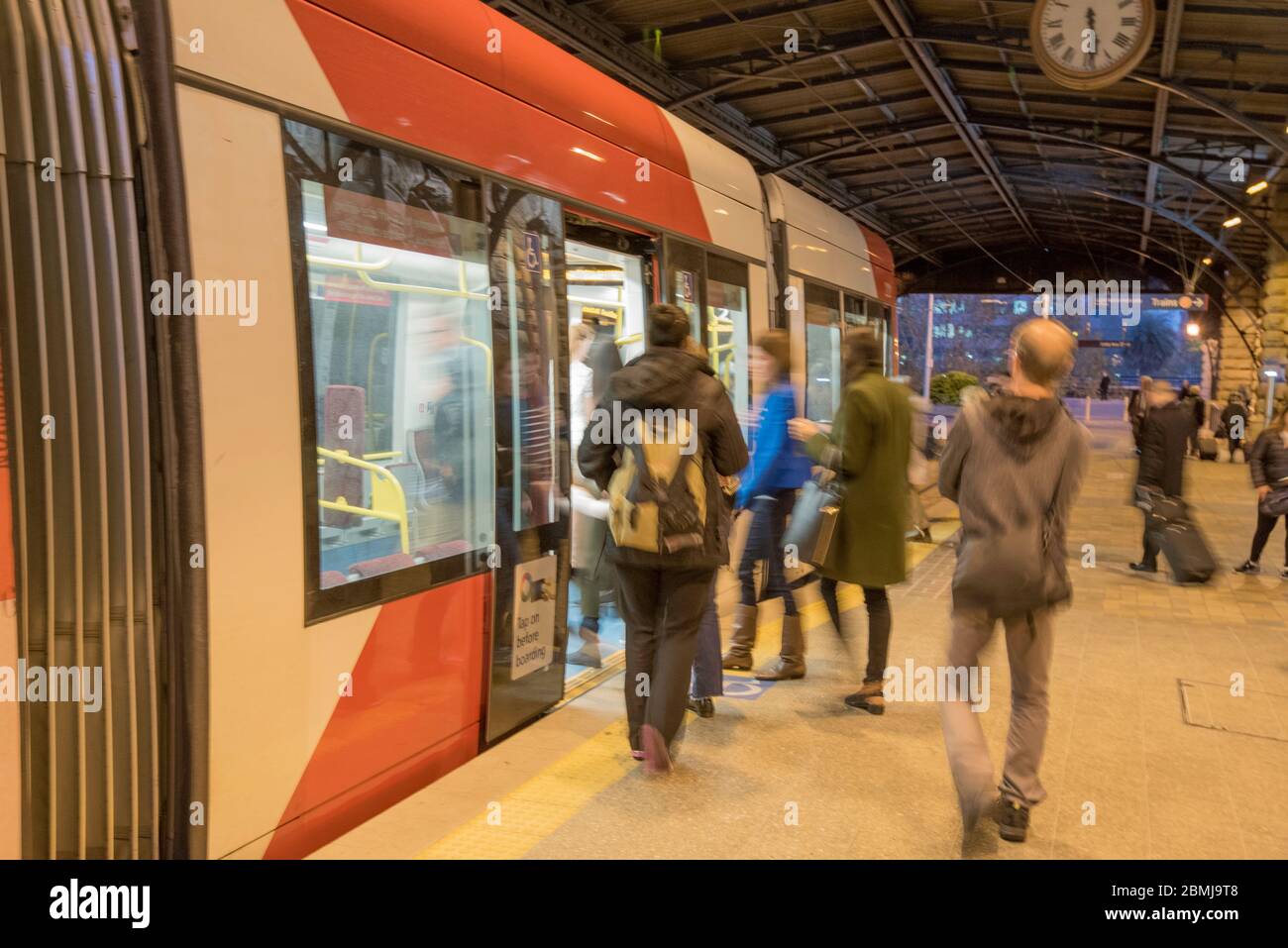 Commuters (blurred) boarding a light rail tram at Central Station during the evening commute in Sydney, Australia Stock Photo