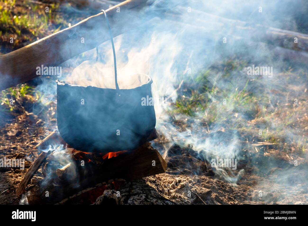 steaming old pot outdoor. cooking and camping. outdoor adventures concept. beaten cauldron on camp fire Stock Photo