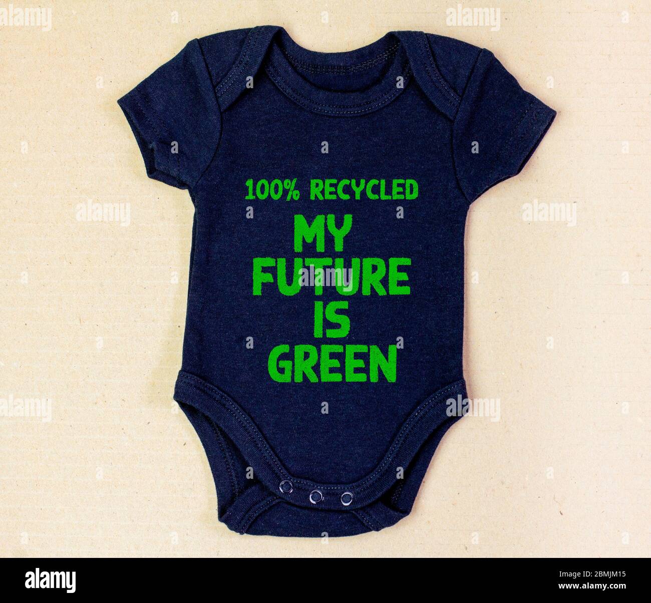 Recycled fabric baby grow with the future is green text on recycled cardboard background. Zero waste and sustainable fashion concept Stock Photo