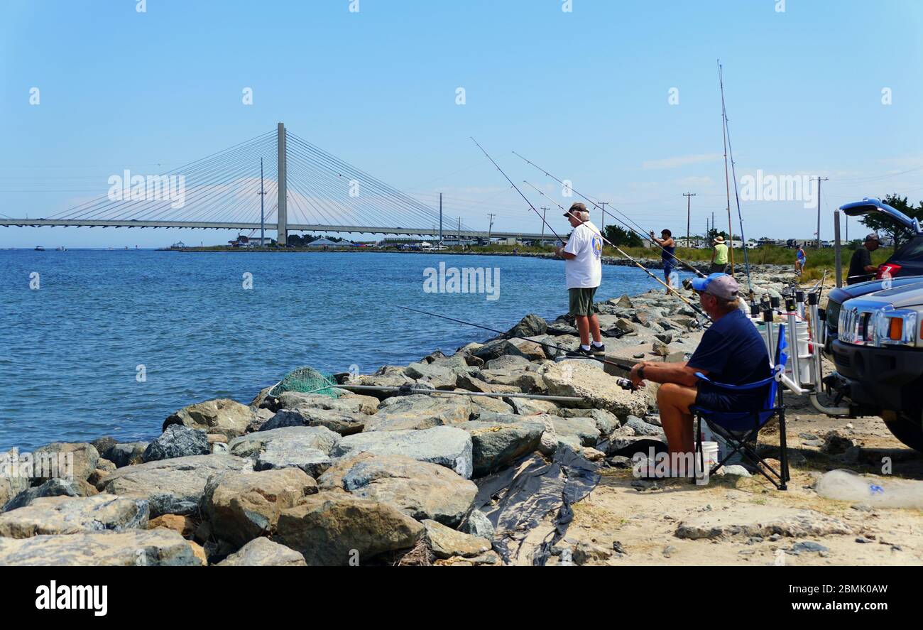 Bethany Beach, Delaware, U.S.A - September 2, 2019 - People fishing for flounder on the rocks by Indian River Inlet Stock Photo