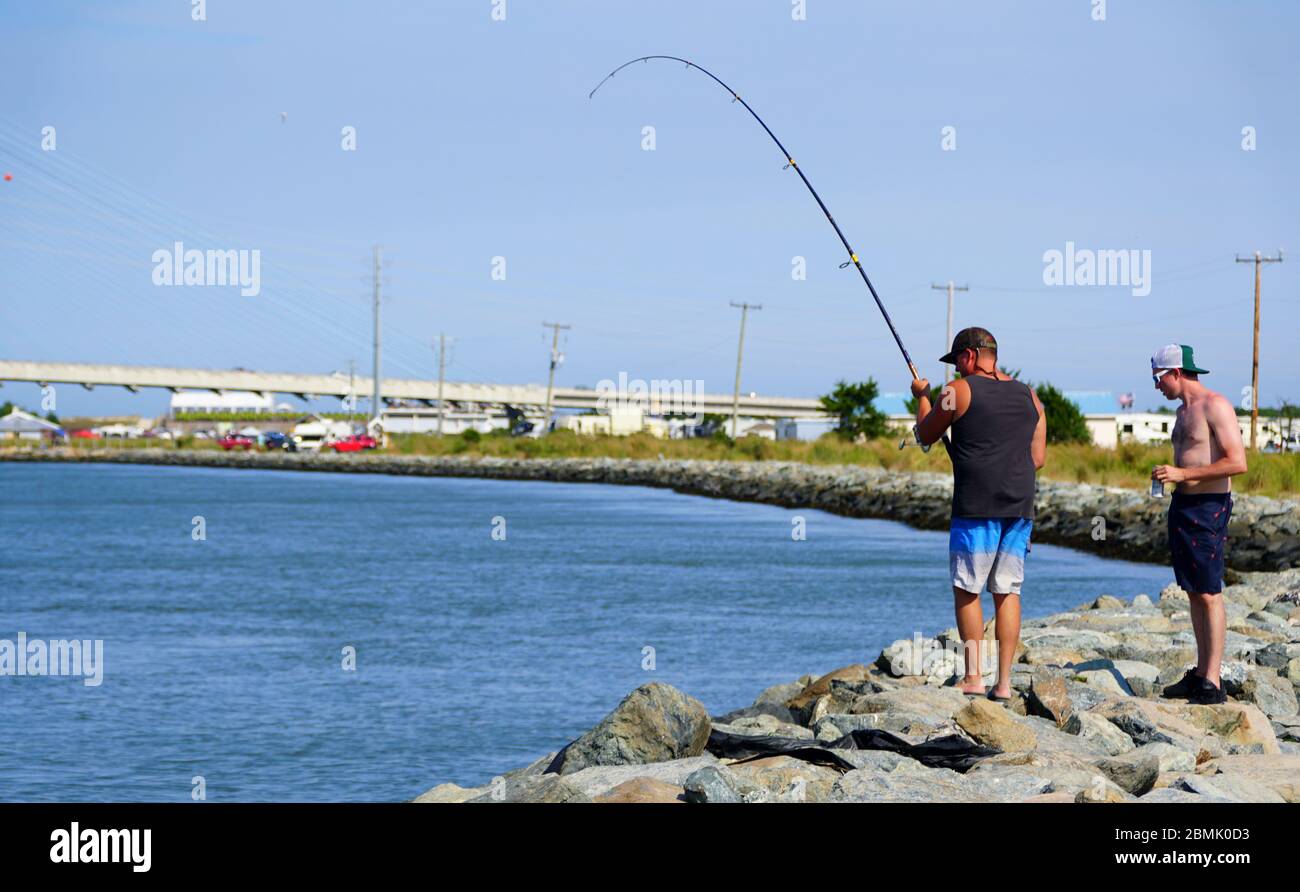 Bethany Beach, Delaware, U.S.A - September 2, 2019 - A man fishing by the rocks by Indian River Inlet Stock Photo