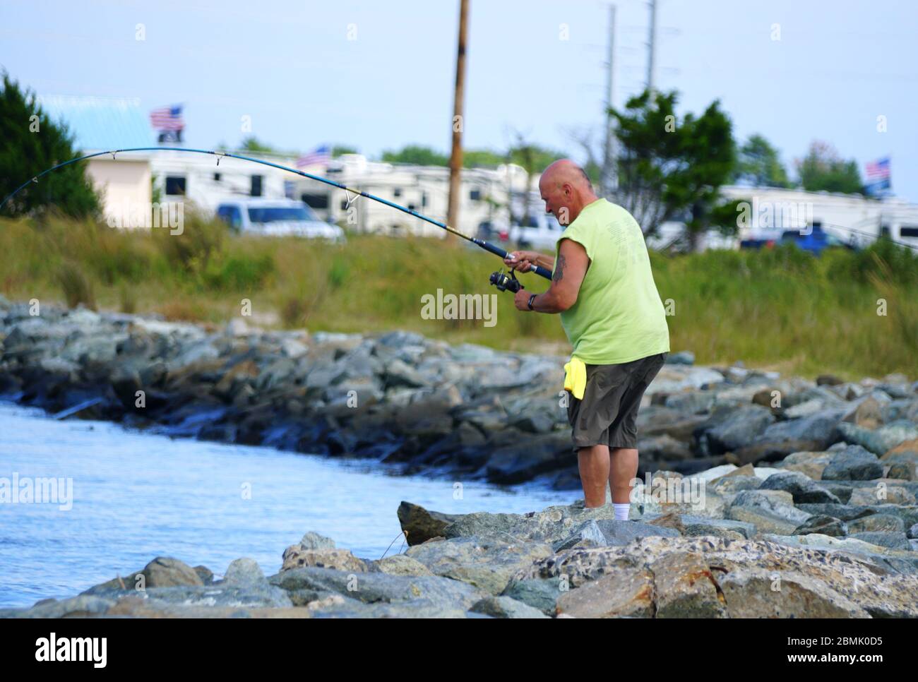 Bethany Beach, Delaware, U.S.A - September 2, 2019 - A man fishing by the rocks by Indian River Inlet Stock Photo