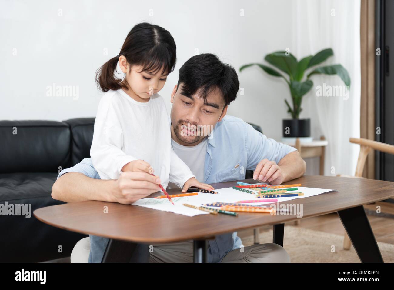 A pair of young Asian father and daughter are drawing in the living room Stock Photo