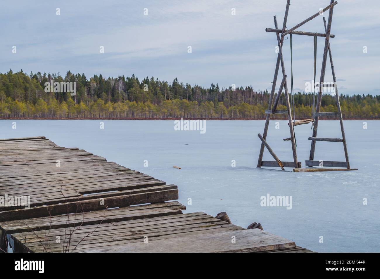 Swing on a frozen lake. solitude concept. wooden pier on the shore. nature landscape Stock Photo