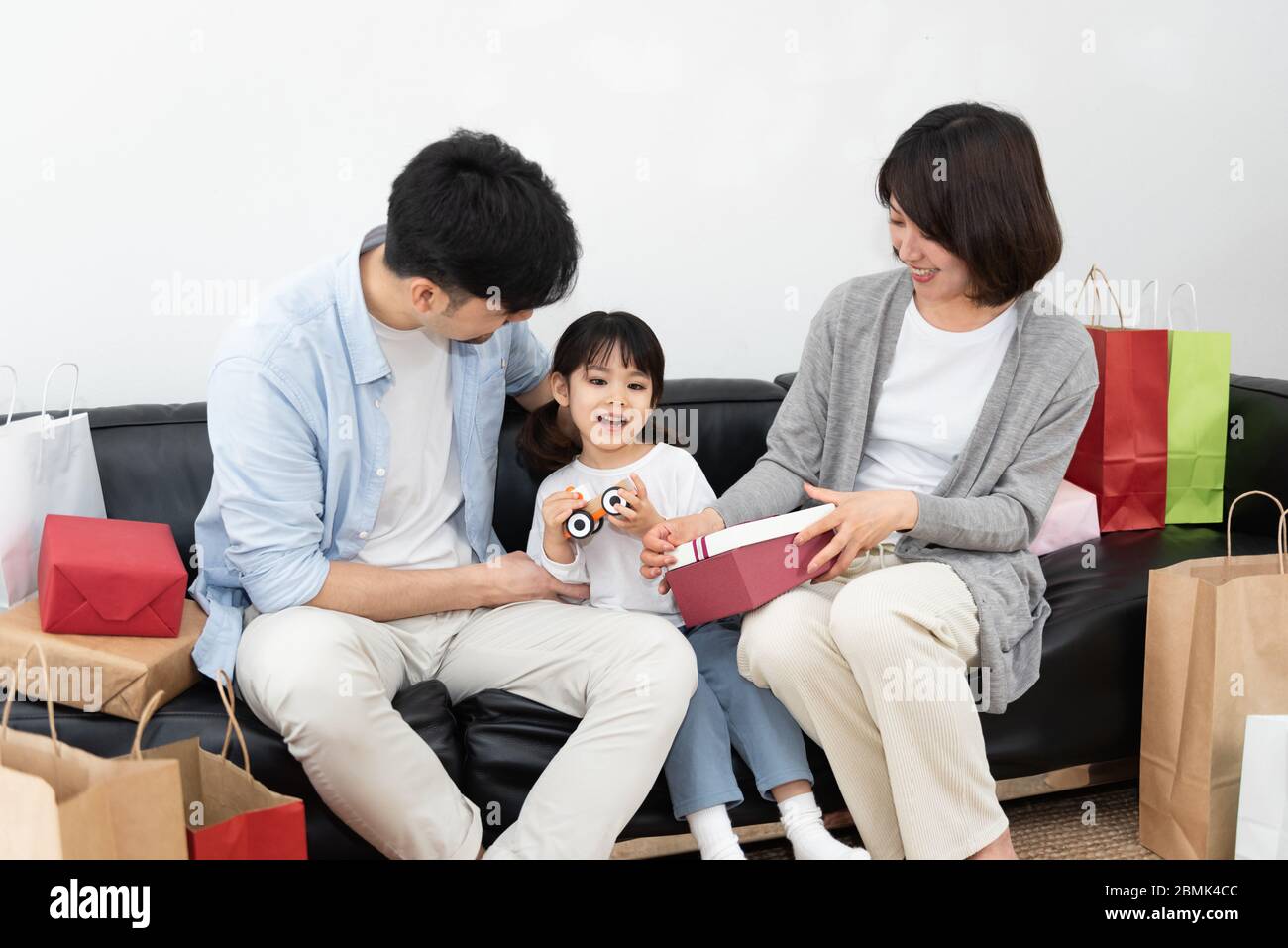 https://c8.alamy.com/comp/2BMK4CC/young-asian-mom-and-dad-are-unpacking-gifts-with-their-daughter-2BMK4CC.jpg