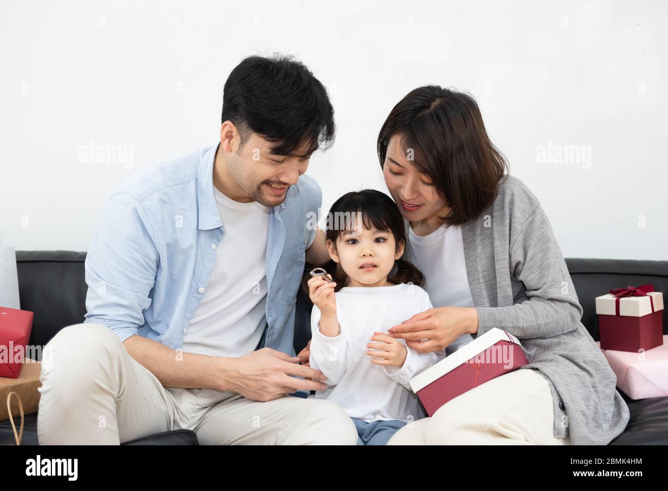 https://c8.alamy.com/comp/2BMK4HM/young-asian-mom-and-dad-are-unpacking-gifts-with-their-daughter-2BMK4HM.jpg