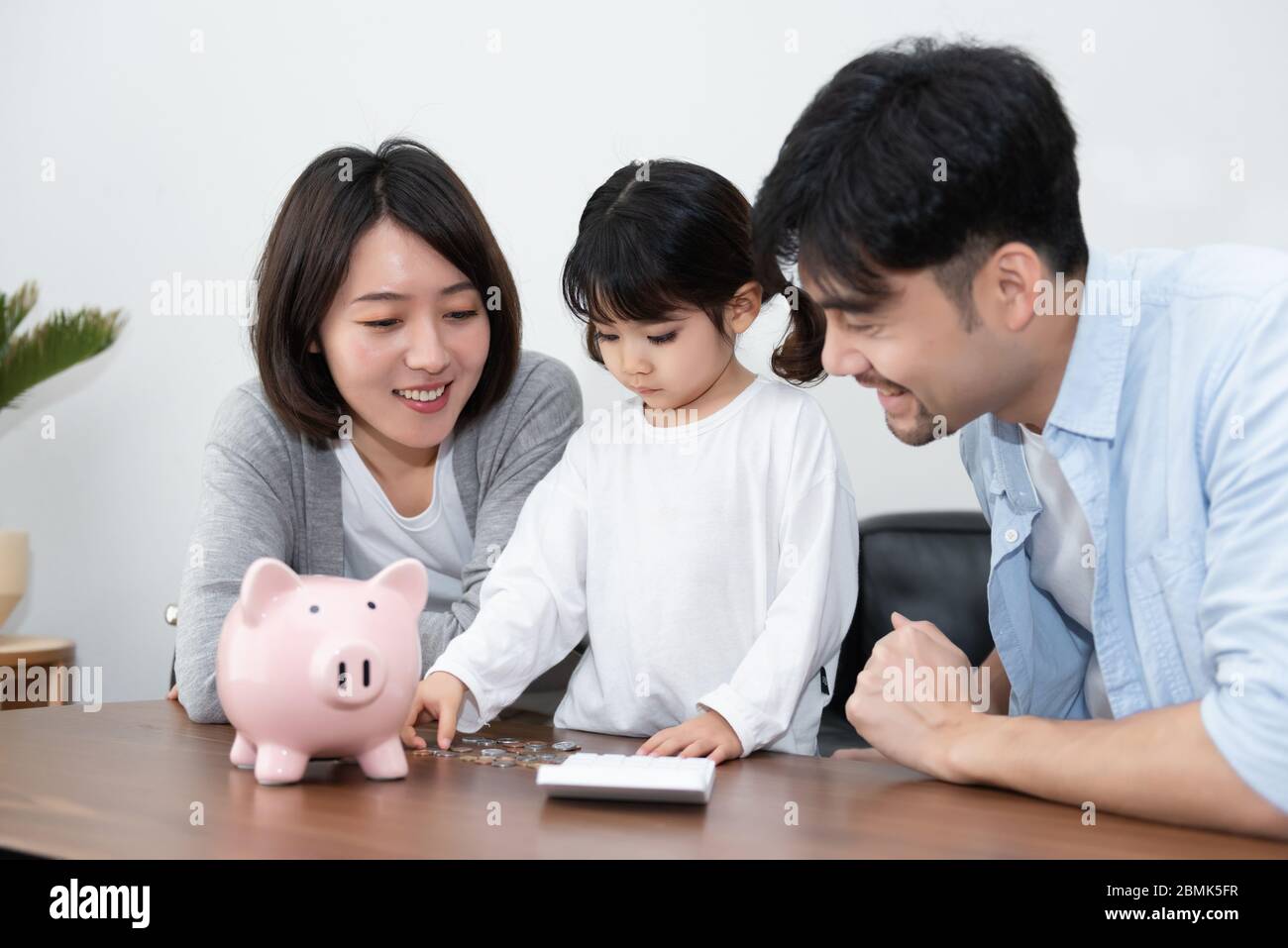 Young Asian mom and dad are saving money with daughter Stock Photo