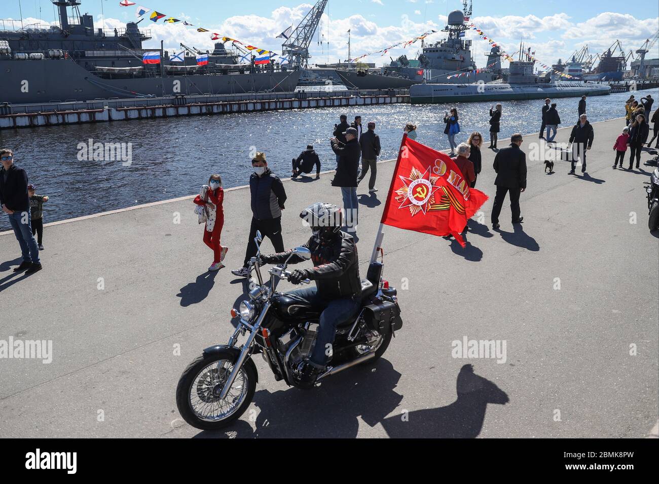 Saint Petersburg, Russia. 09th May, 2020. People are seen on the embankment of the Neva River while a motorcycle pass through during the Victory Day celebration.Victory Day celebrated on May 9 in Russia, the ground part of the parade was postponed as a preventive measure against the spread of the coronavirus disease (COVID-19) pandemic Credit: SOPA Images Limited/Alamy Live News Stock Photo