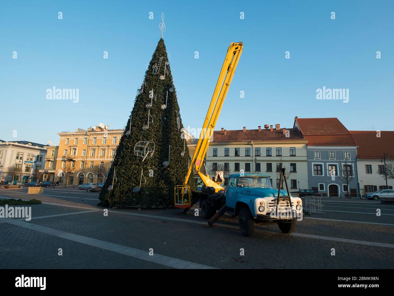 A truck preps a giant, fake Christmas tree in the Old Town Rotušė square. In Vilnius, Lithuania. Stock Photo