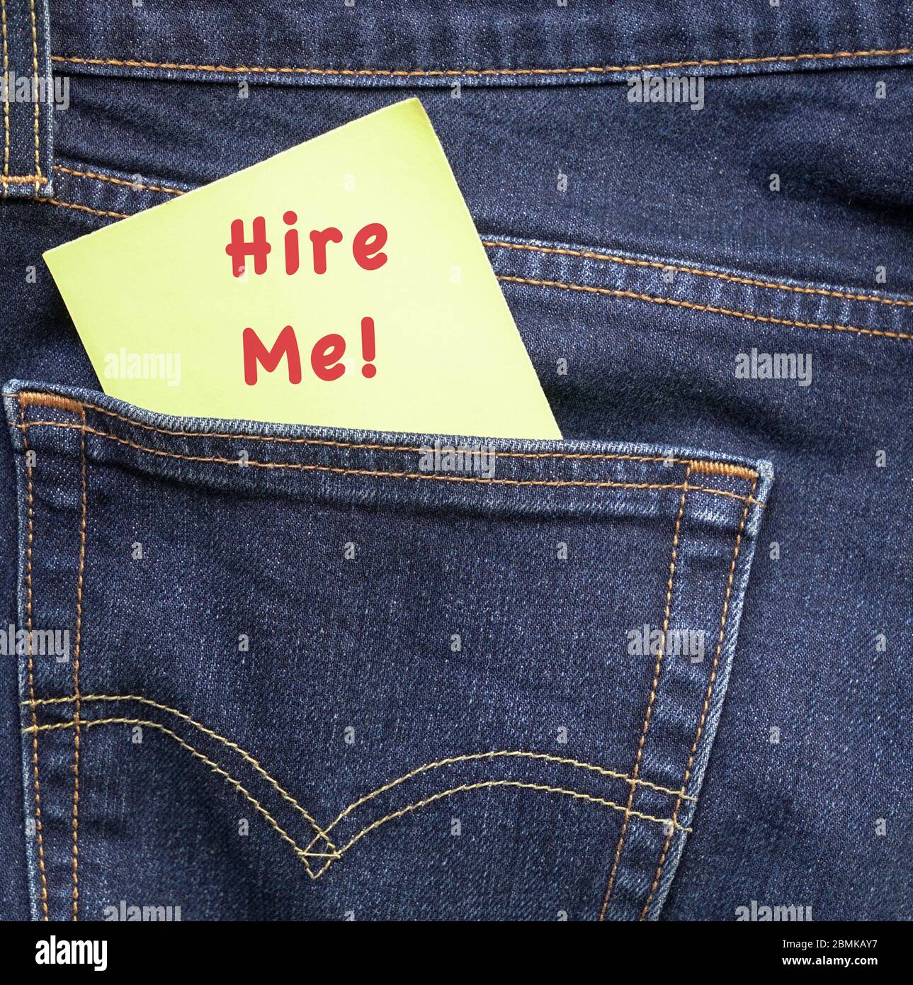 Hire me, words in red on a yellow paper stuck out from jeans pocket. Employment or jobs concept. Stock Photo