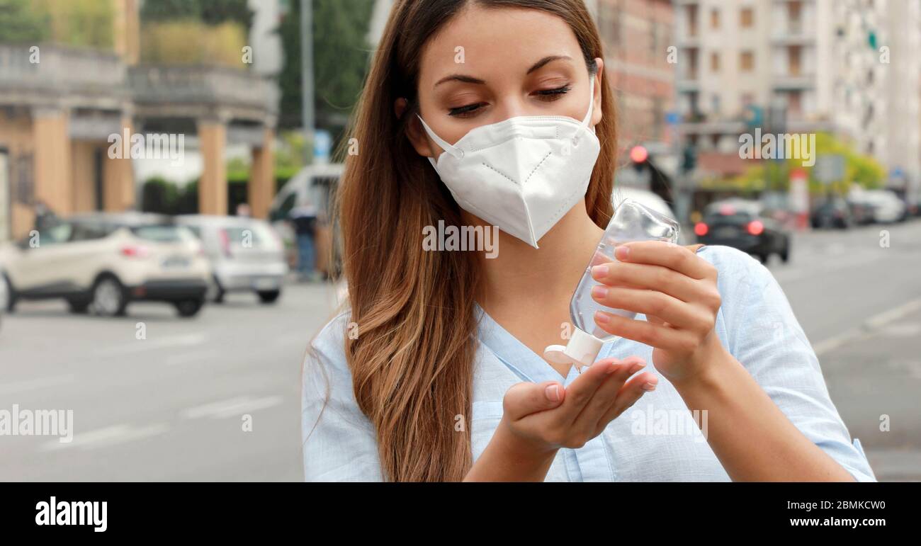 COVID-19 Pandemic Coronavirus Close up Woman with KN95 FFP2 Mask using Alcohol Gel Sanitizer Hands in City Street. Antiseptic, Hygiene and Healthcare Stock Photo