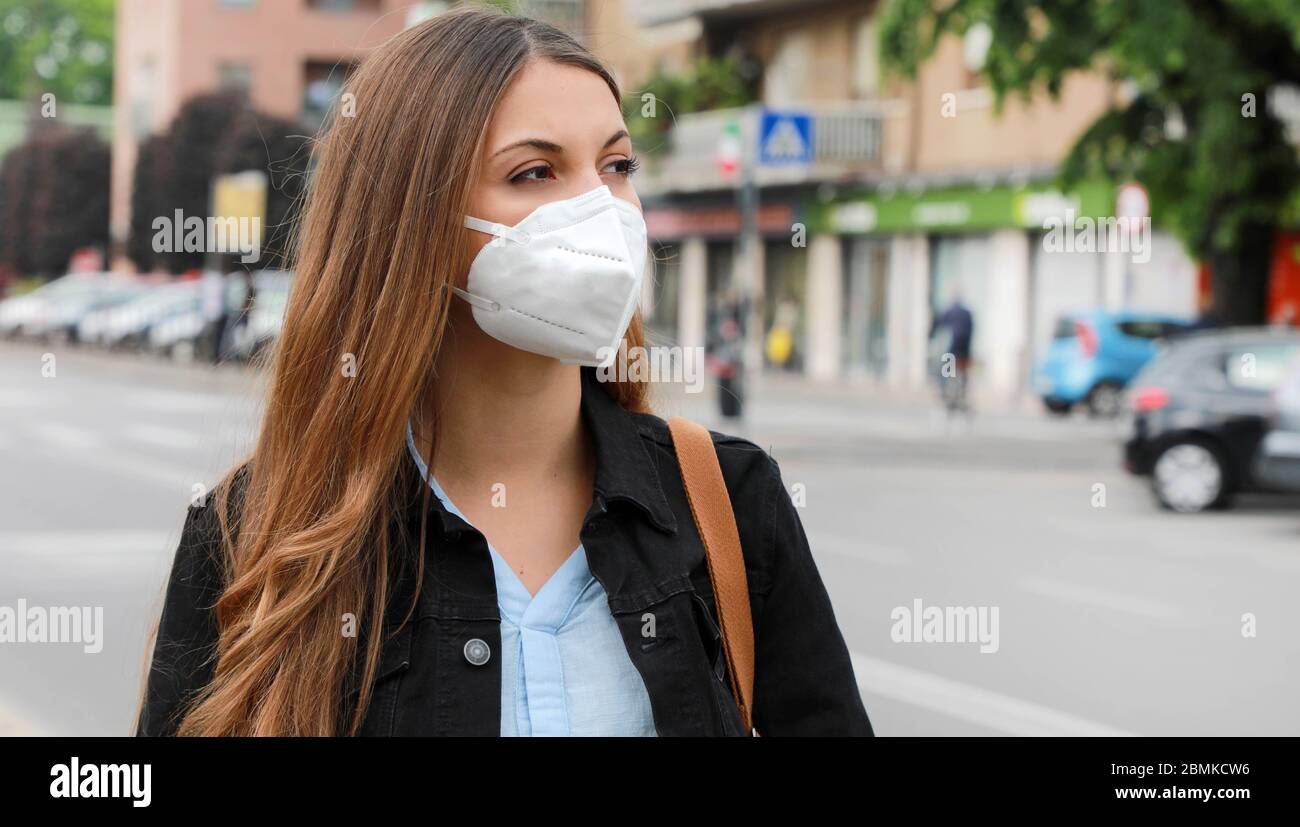 COVID-19 Pandemic Coronavirus Woman in city street wearing KN95 FFP2 mask protective for spreading of disease virus SARS-CoV-2. Girl with protective m Stock Photo